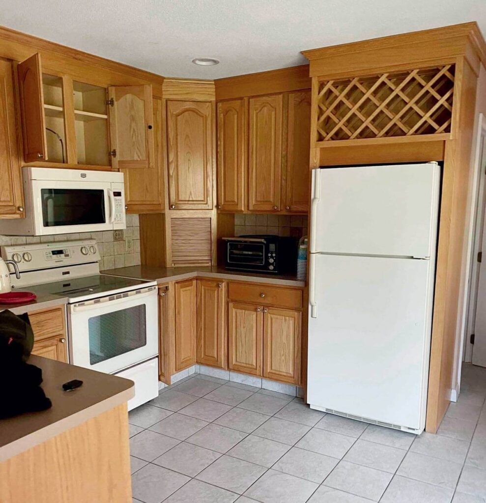 Kitchen with wooden cabinets, white appliances, a microwave, oven, fridge, and a wine rack above the refrigerator.