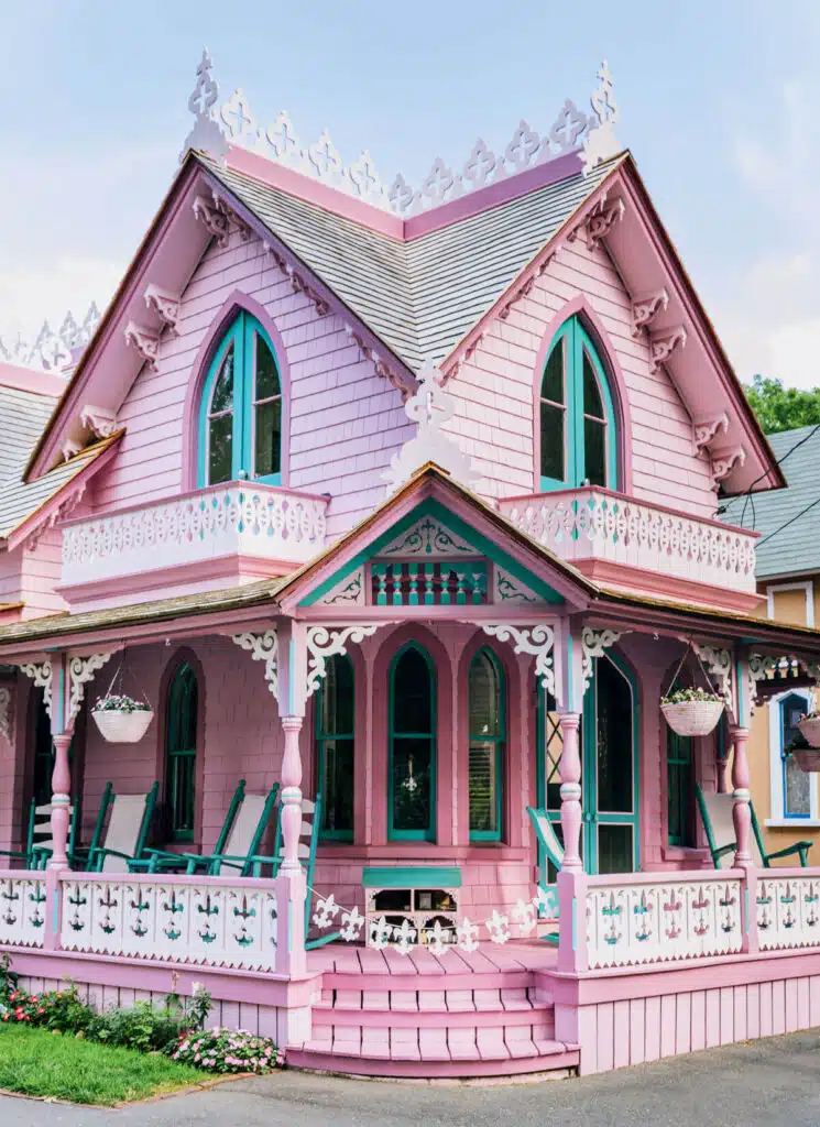 New England Victorian Gingerbread Houses. A whimsical pink Victorian house with teal trim, ornate white detailing, and a wraparound porch.