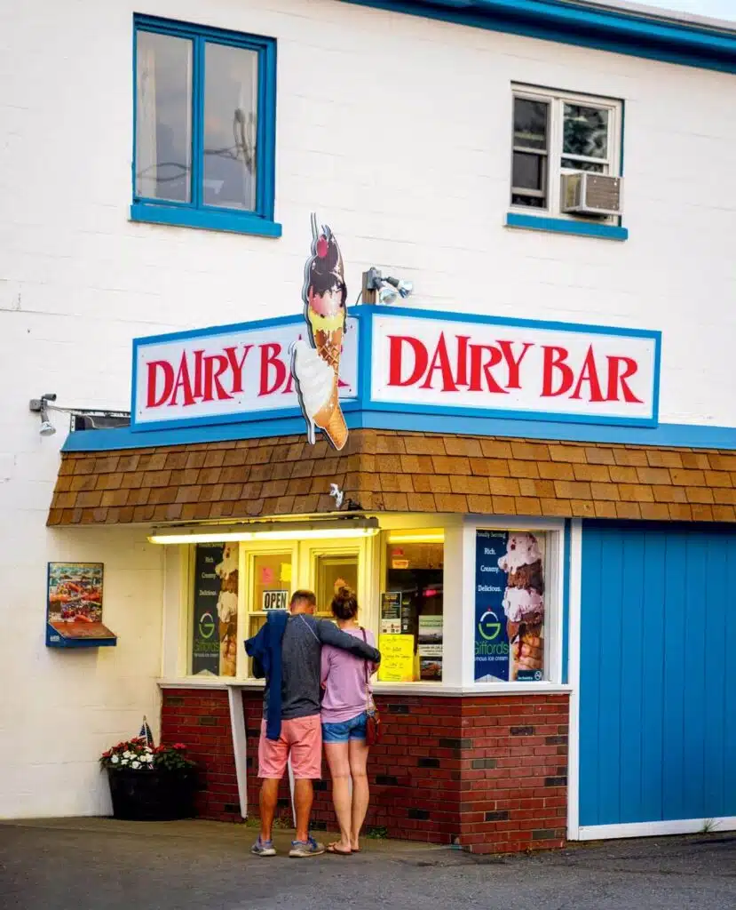 A couple stands at the window of a Dairy Bar ice cream shop with a cone sign above.