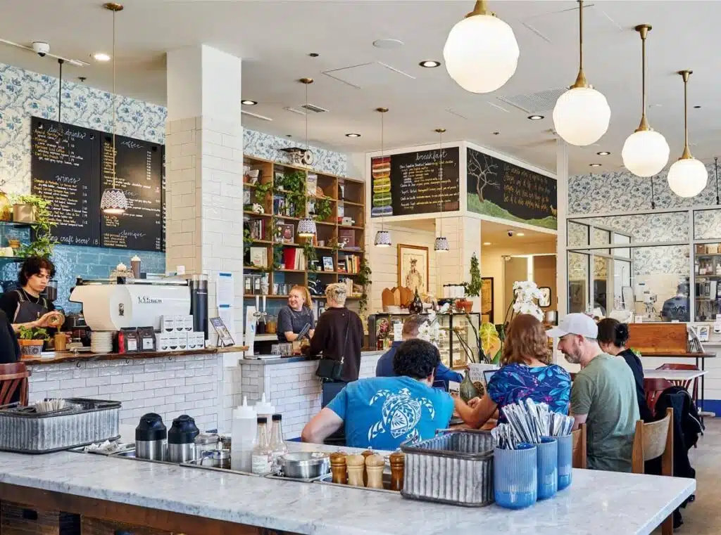 A bright, busy café with people sitting at tables and staff working behind the counter.