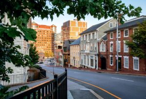 Spring Weekend in Providence, Rhode Island. Curved city street lined with historic brick and wooden buildings, framed by leafy green tree branches.