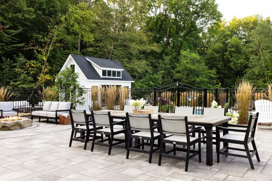 Spacious patio with a large dining table, chairs, lounge seating, fire pit, and a small white shed in the background.