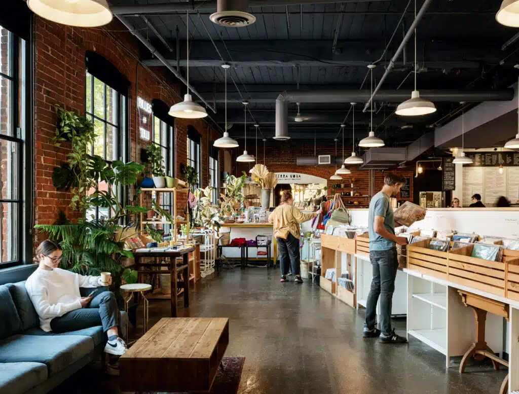 2026 New Hampshire Travel Guide. A cozy, modern shop with vinyl records, plants, and people browsing or relaxing with coffee.