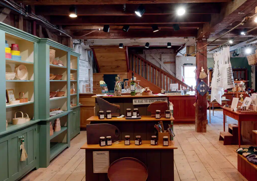 2026 New Hampshire Travel Guide. Rustic shop interior with wooden shelves, cutting boards, jars, and various handmade crafts on display.
