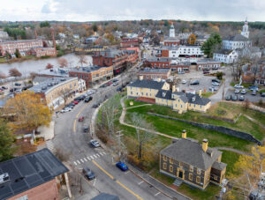 Aerial view of a small historic town with brick buildings, churches, and autumn trees.