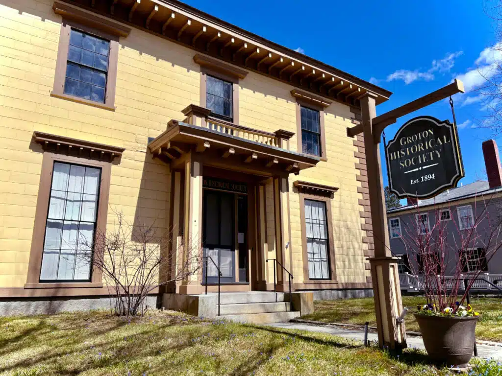Yellow historic Boutwell House in Groton, MA, with a sign reading Groton Historical Society.