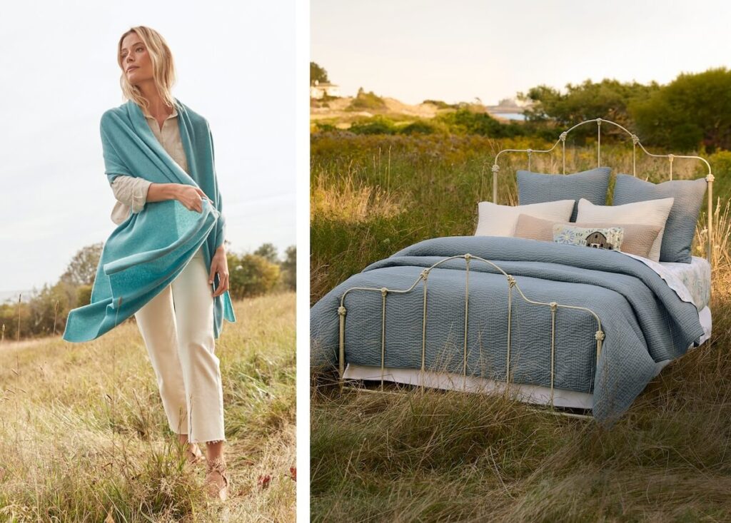 Woman in a blue shawl stands in a field; bed with blue bedding is set outdoors in grassy landscape.
