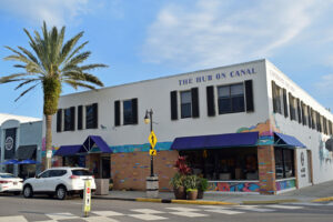 A two-story building with blue awnings labeled “The Hub on Canal” on a sunny street corner.