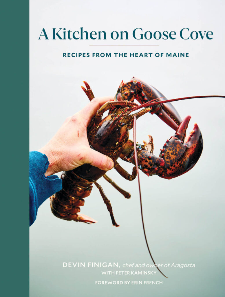 A hand holding a large live lobster in front of the book title "A Kitchen on Goose Cove.