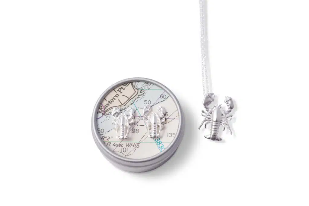 Patsy Kane silver lobster earrings on a map tin and a matching lobster necklace on a white background.