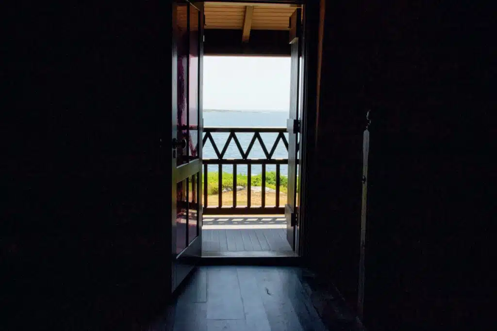 Winslow Homer's Studio in Scarborough, Maine. A sunlit ocean view seen through an open doorway leading to a balcony with a wooden railing.