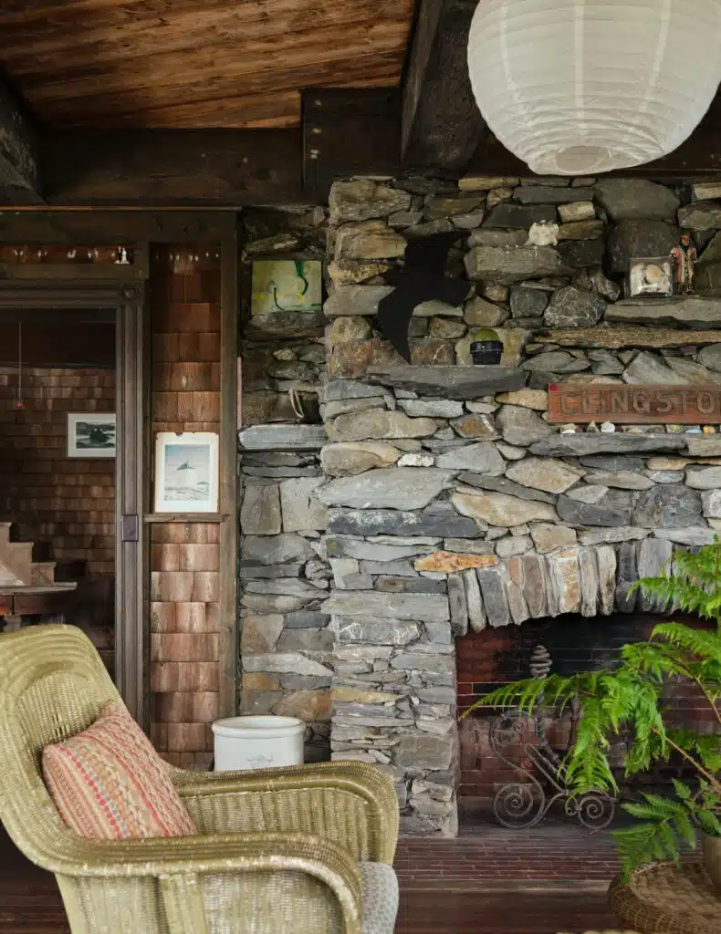 Stone fireplace with a black bat decor, wicker chair, and paper lantern in a cozy rustic room.