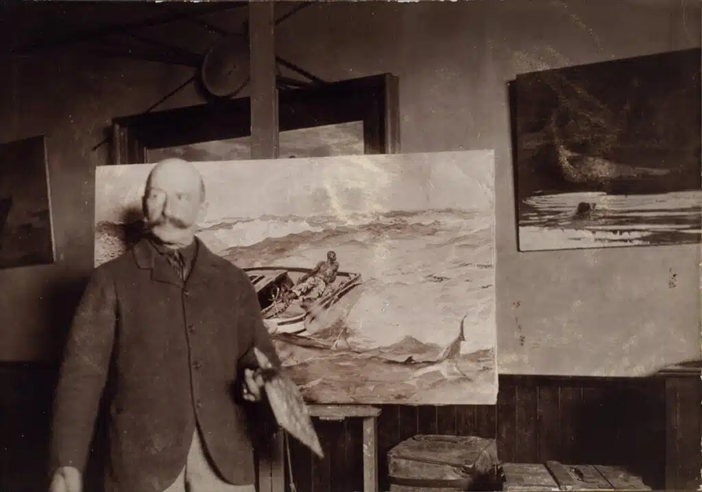 Winslow Homer's Studio in Scarborough, Maine. An artist stands in front of a seascape painting with boats, holding a palette, in a studio.