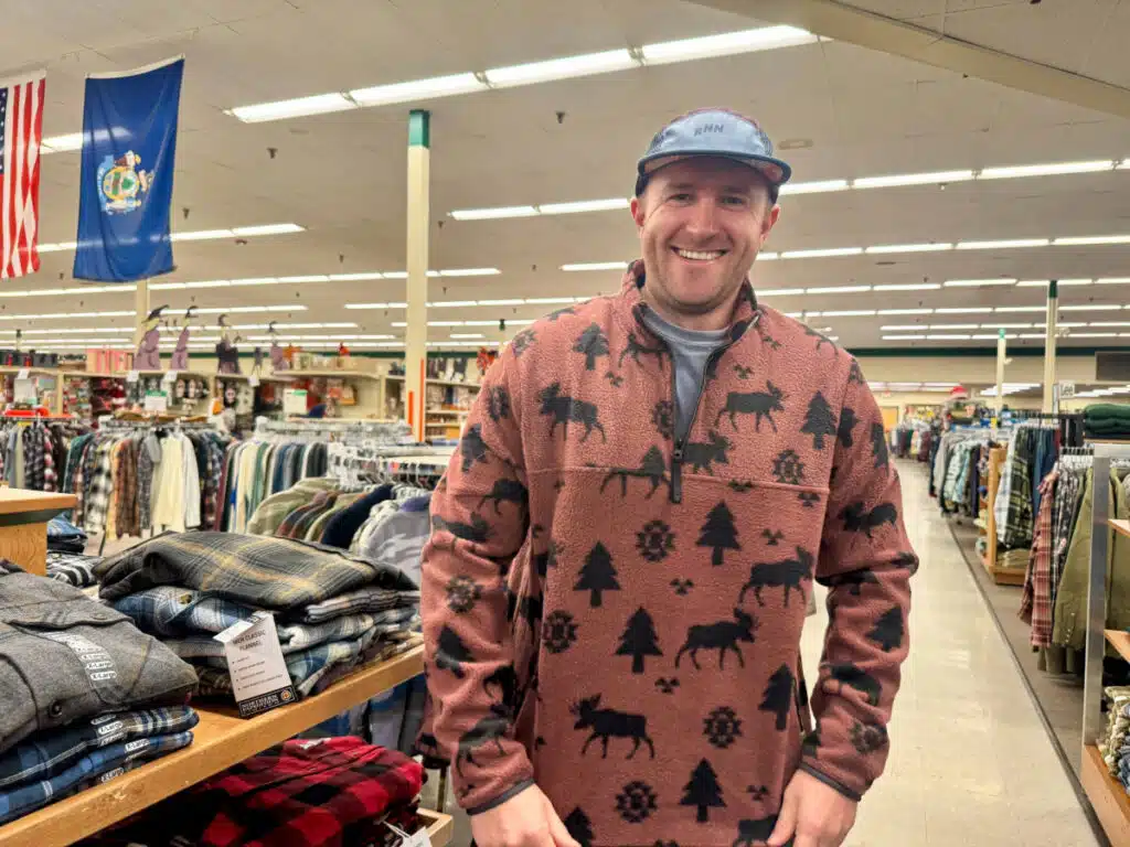 Smiling man in a moose fleece stands in a Renys store in Maine.