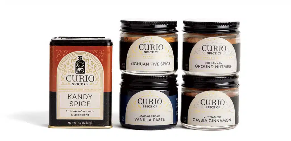 One tin and four glass jars of Curio Spice Co. spices.