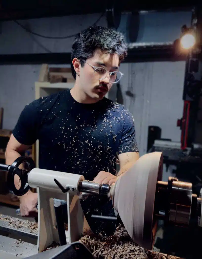 A woodworker shapes a bowl on a lathe.