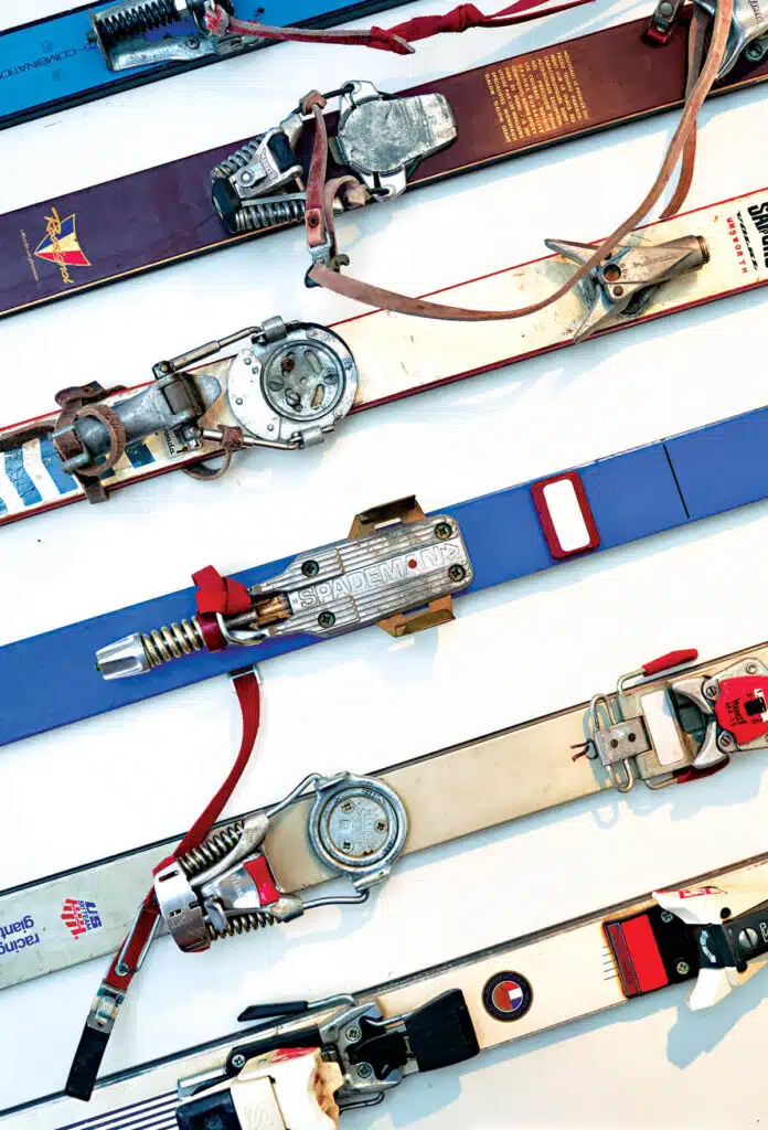 Five pairs of vintage skis with bindings arranged side-by-side.