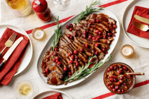 Braised Cranberry-Rosemary Brisket. Sliced brisket topped with cranberry glaze and fresh rosemary on a serving platter.