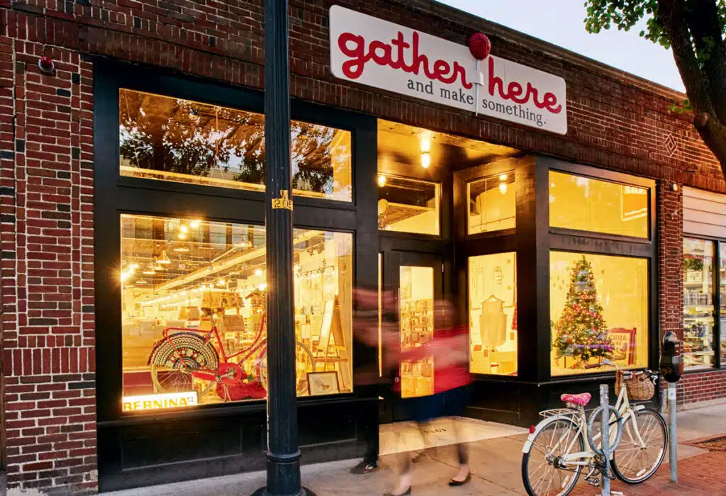 Storefront for “gather here and make something” with a decorated bicycle parked outside.
