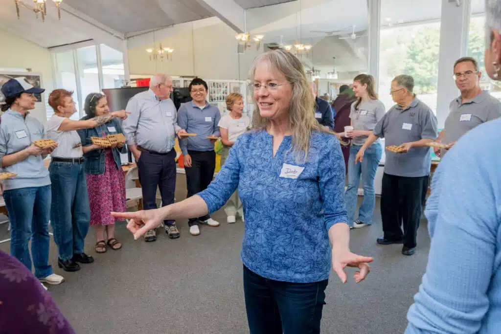 A group of people wearing name tags holding wooden game boards in a community room.