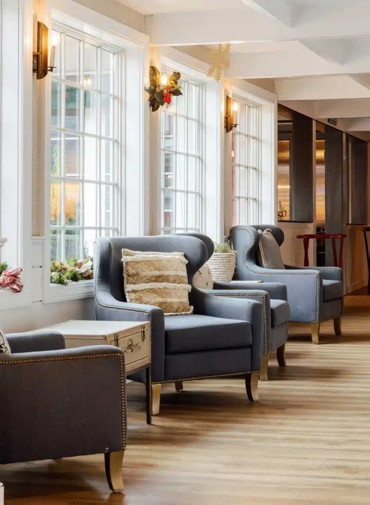 Three blue upholstered armchairs arranged along a row of windows.