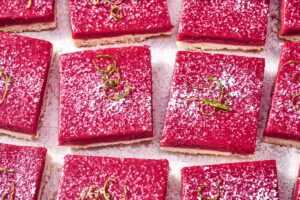 Cranberry-Lime Bars. Square slices of bright pink berry bars topped with powdered sugar and lime zest.
