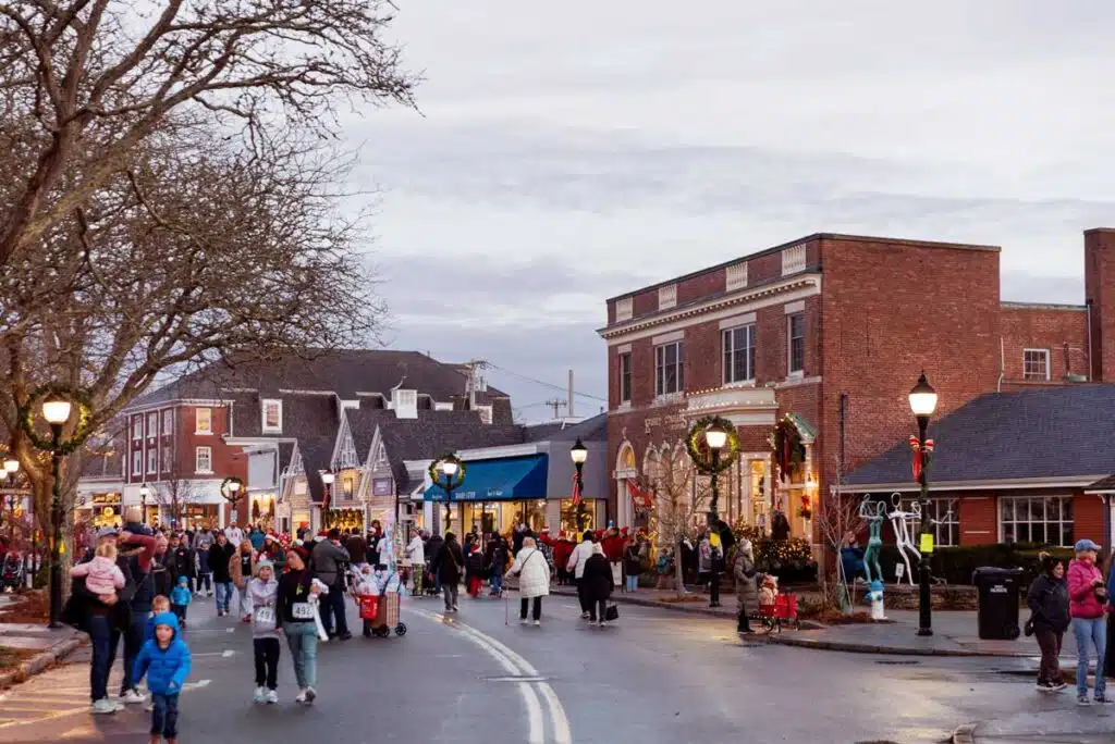 Crowd of people walking on a town street decorated for the holidays.