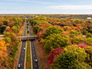Aerial view of a highway passing through a forest of autumn trees.