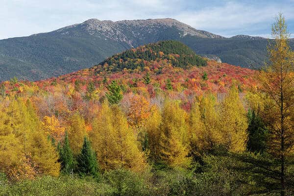 Mountains covered in autumn foliage with vibrant red, orange, and yellow trees.