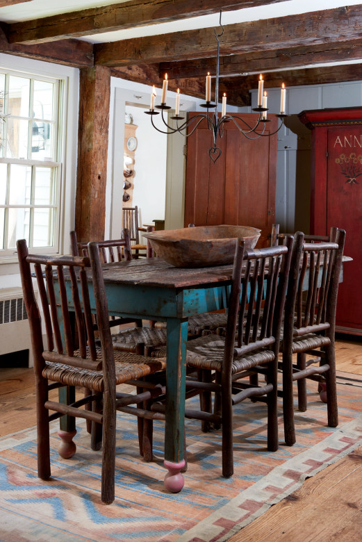 Melding the antique with the artistic, the dining room features primitive furniture from the early 1800s lit by a wrought-iron chandelier.
