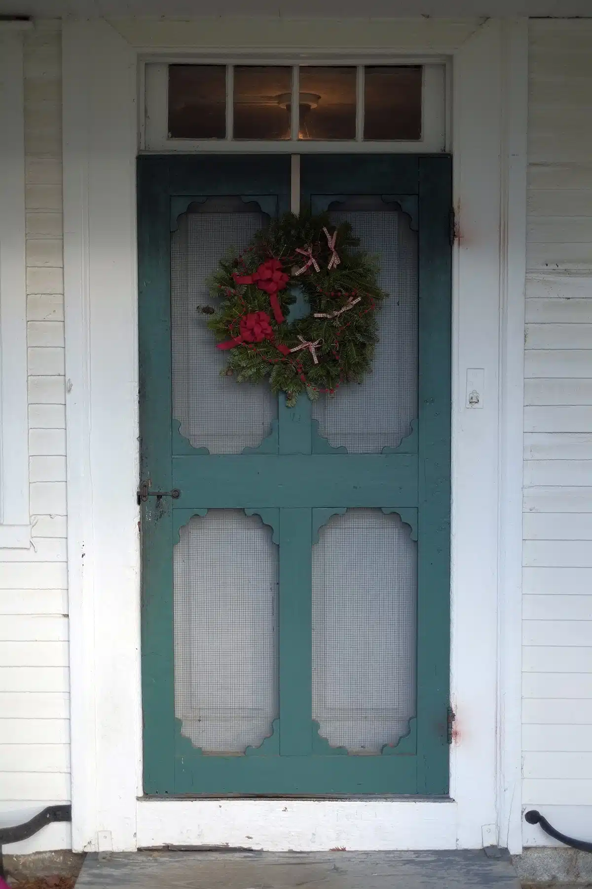 Red ribbons decorate a wreath on the entrance door to the kitchen in the bottom floor of the Dwelling House.