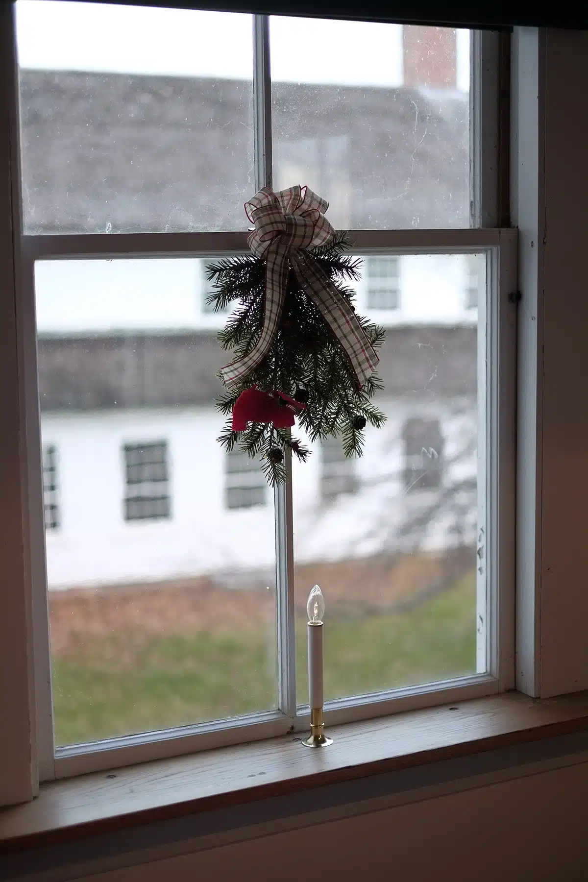 Fresh swag with a red Scottie Dog ornament and plaid ribbon hangs in the window of the Spin Shop looking out to the Dry House.