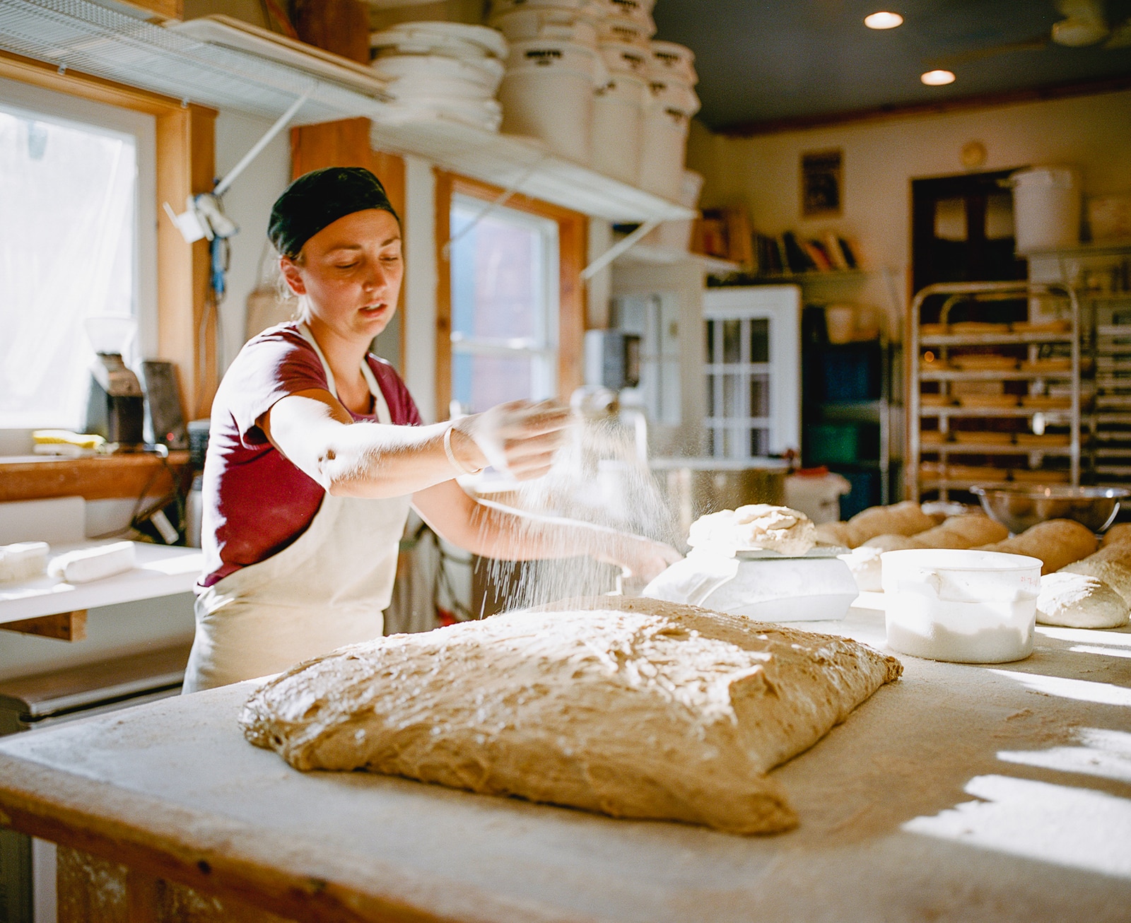 Title: Untitled, 2016 Location: Elmore, VT Judge's comments: "While some would see this image as being more commercial art than fine-art, some images can straddle multiple genres. One could see this photograph as editorial, since it illustrates the story behind a baker’s business. The image also stands alone as an environmental portrait of a New England baker. The artist utilizes the figure and the bread dough to capture our focus. A room bathed in light, a limited palette, the motion of the flour and the color of the baker’s red shirt combine to keep the viewer’s attention on the meditative action of bread-making and to create a sensation as if it were a moving image." 