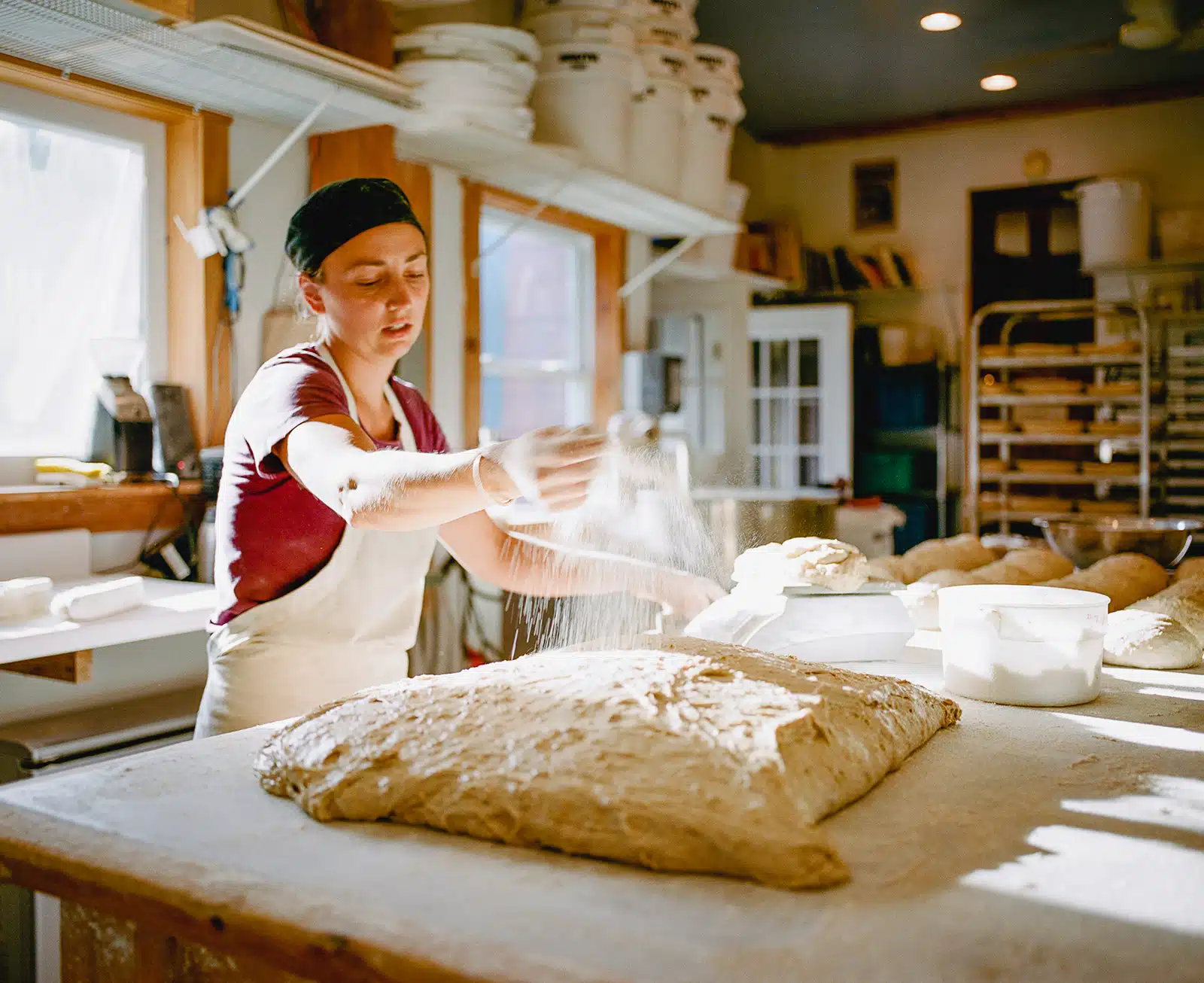 Title: Untitled, 2016 Location: Elmore, VT Judge's comments: "While some would see this image as being more commercial art than fine-art, some images can straddle multiple genres. One could see this photograph as editorial, since it illustrates the story behind a baker’s business. The image also stands alone as an environmental portrait of a New England baker. The artist utilizes the figure and the bread dough to capture our focus. A room bathed in light, a limited palette, the motion of the flour and the color of the baker’s red shirt combine to keep the viewer’s attention on the meditative action of bread-making and to create a sensation as if it were a moving image."