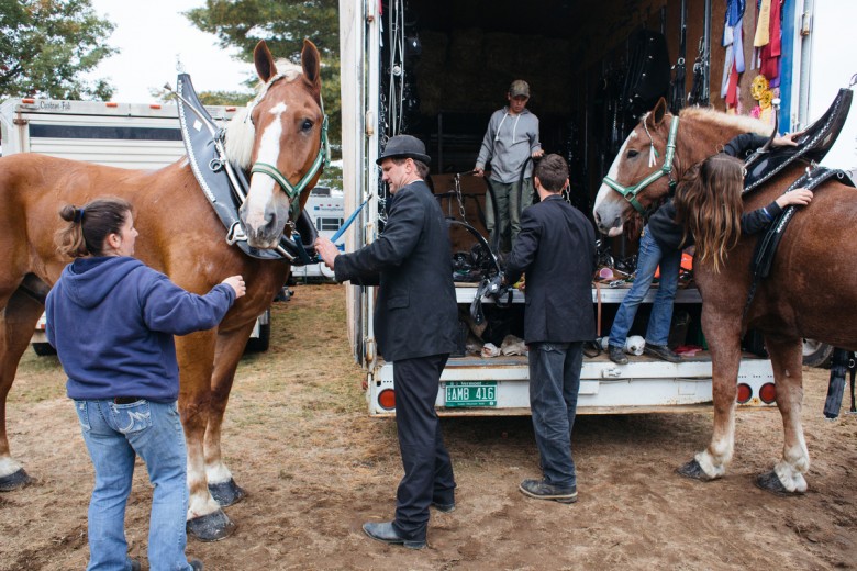 Jennifer Lang, left, her husband, Sean Lang, second from left, and their family, all of Hinesburg, Vermont, unharness their draft horses after marching in the Grand Parade.