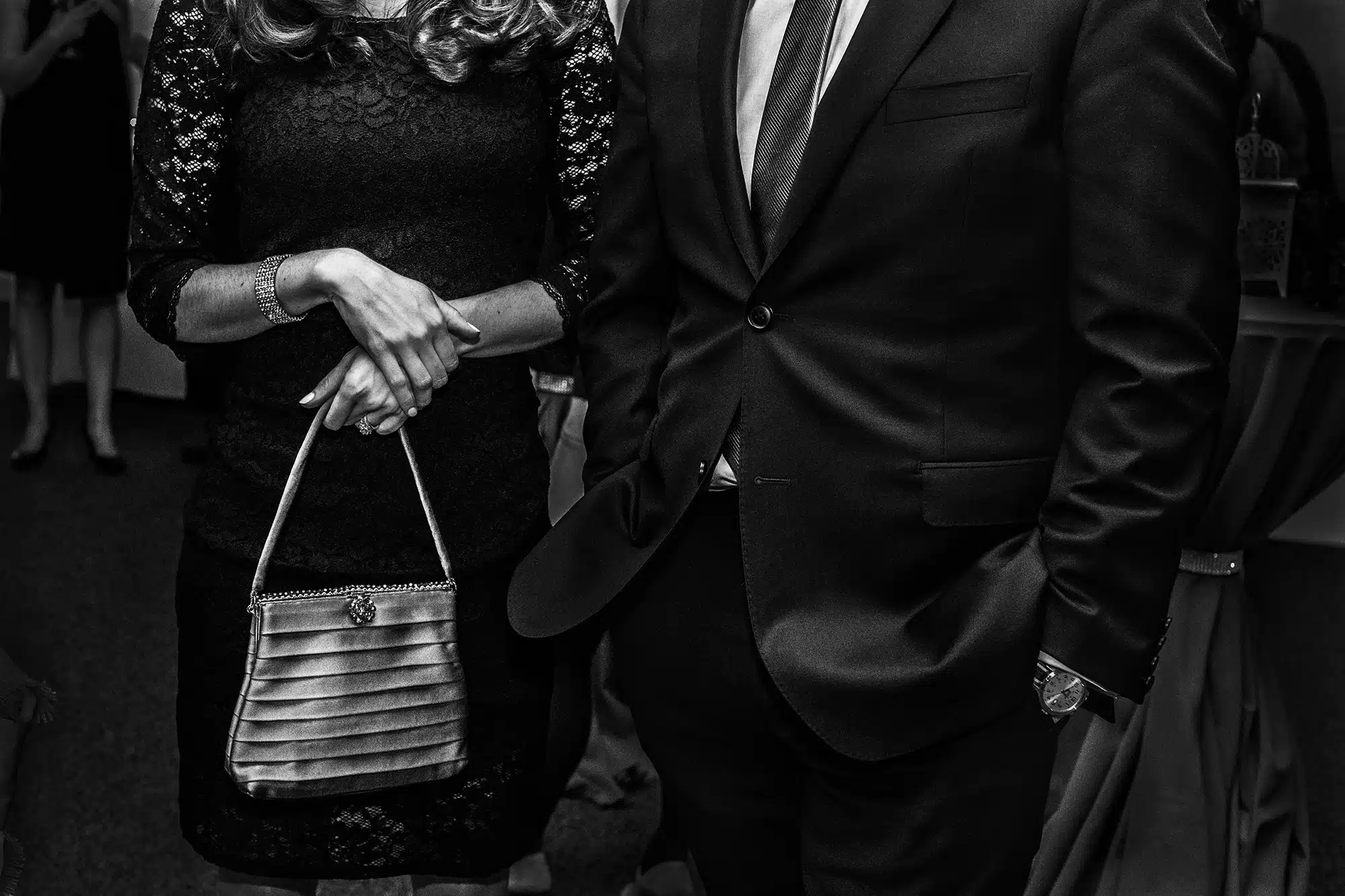 Fundraiser - 2015 "I went to this black tie fundraiser for many years as a guest and supporter but this year I went as a fly on the wall. It was very dark and there was a lot of pink and purple light. I quickly decided to shoot tight details in black and white, much like Larry Fink’s work of the fashion world and high society. I was attracted to a beautiful woman’s delicate hands holding a vintage pocket book juxtaposed with the gentleman’s watch. As it turns out this image was posted on a photography site and Larry Fink made this comment -‐ ‘This picture with it’s wristwatch time ticking away…each layer of density of description is loaded with a latent sense of fulfillment, the bodies describe folks just waiting in place , waiting to bolt in slow motion to another scenario filled with dreadful ennui."