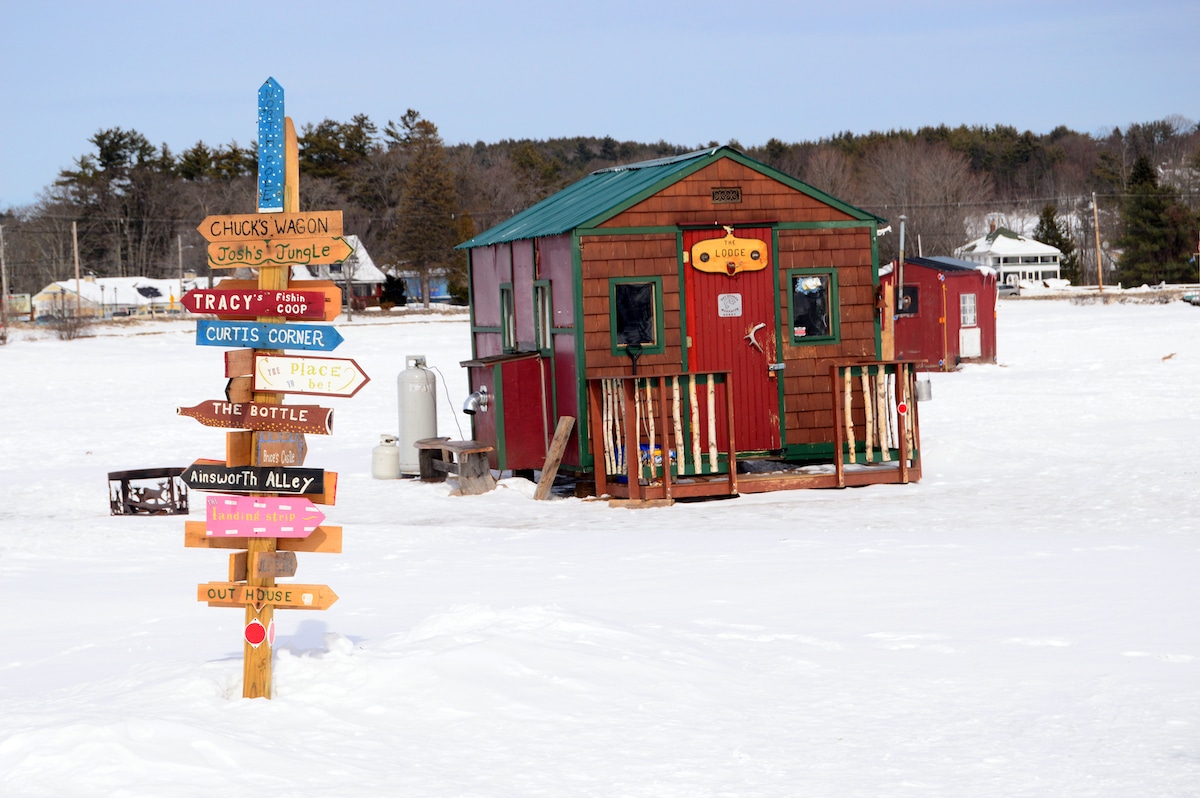 Signs and Ice Fishing Shacks on a Frozen Lake