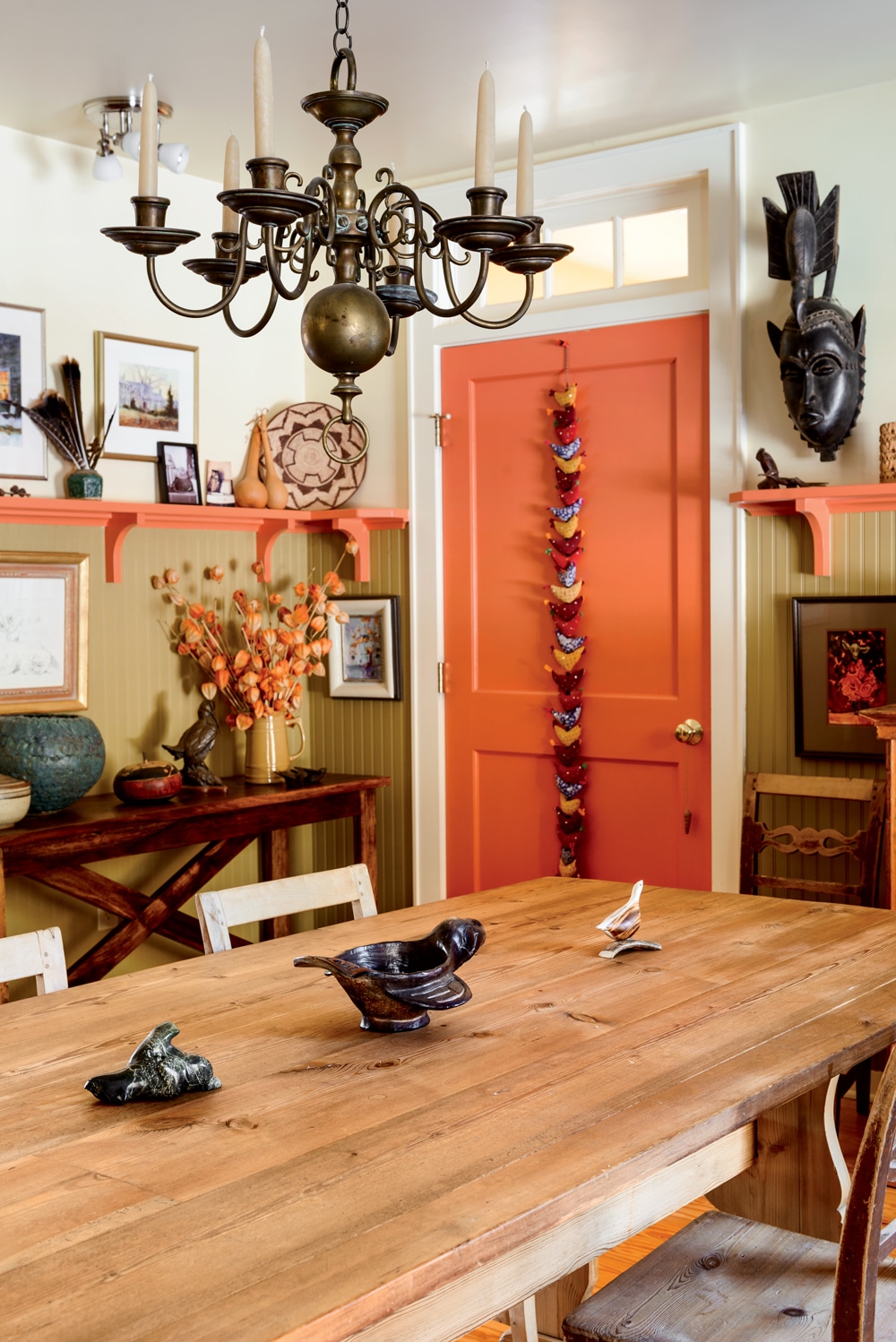 The dining room’s high beadboard wainscoting strikes a traditional note amid exotic artifacts.