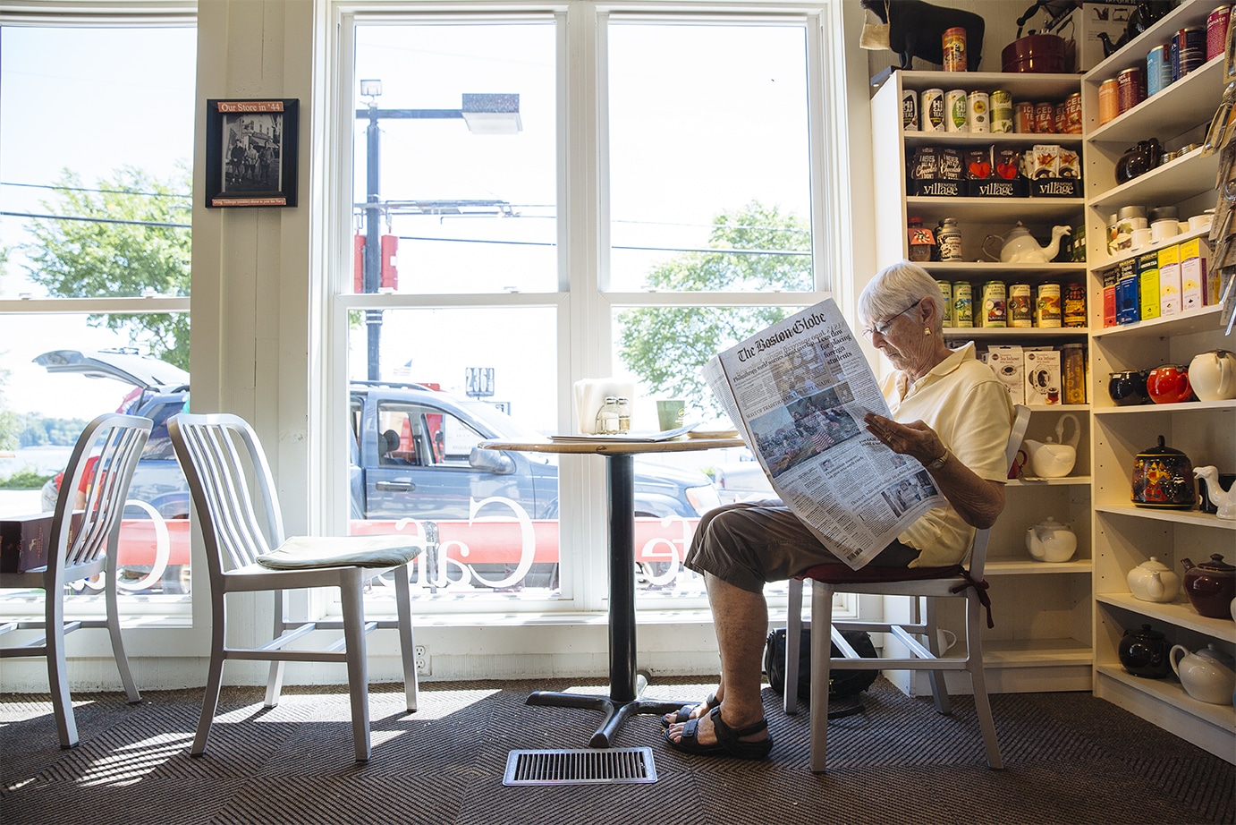 Judy Caldwell of Holderness NH reads a paper at Hero's Welcome General Store. She's en route to visit her mother in Canada and always stops in.