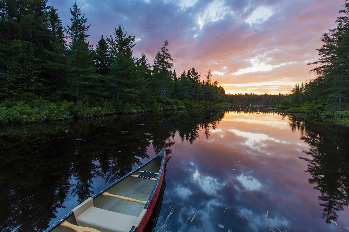 A canoe at sunrise on Little Berry Pond in Maine's Northern Forest. Cold Stream watershed, Johnson Mountain Township.
