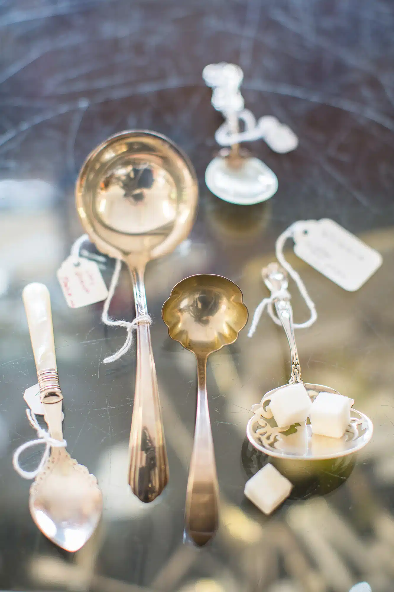 Silver spoons and ladles line a glass table at Antiques on Main.