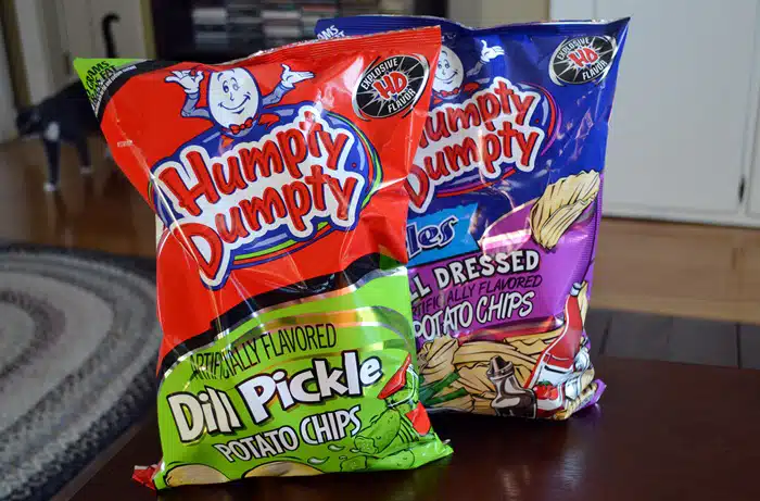 Two bags of Humpty Dumpty potato chips, one Dill Pickle flavor and one All Dressed flavor, on a table, as an example of popular New England food brands.